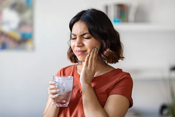 Young woman rubbing her jaw and wincing in pain from a broken filling